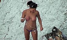 Busty hardbody hottie poserar topless på en strand