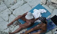 Prietenele bronzate se freacă reciproc pe spate pe o plajă publică de nudiști